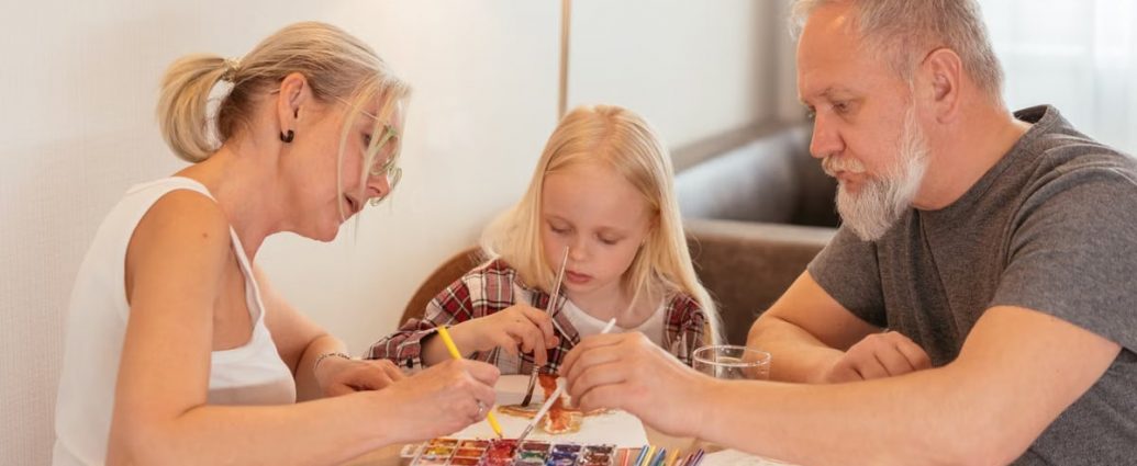 A family of three enjoying creative time with painting and drawing at home.