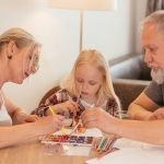 A family of three enjoying creative time with painting and drawing at home.