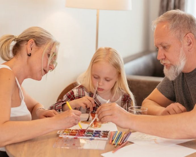 A family of three enjoying creative time with painting and drawing at home.