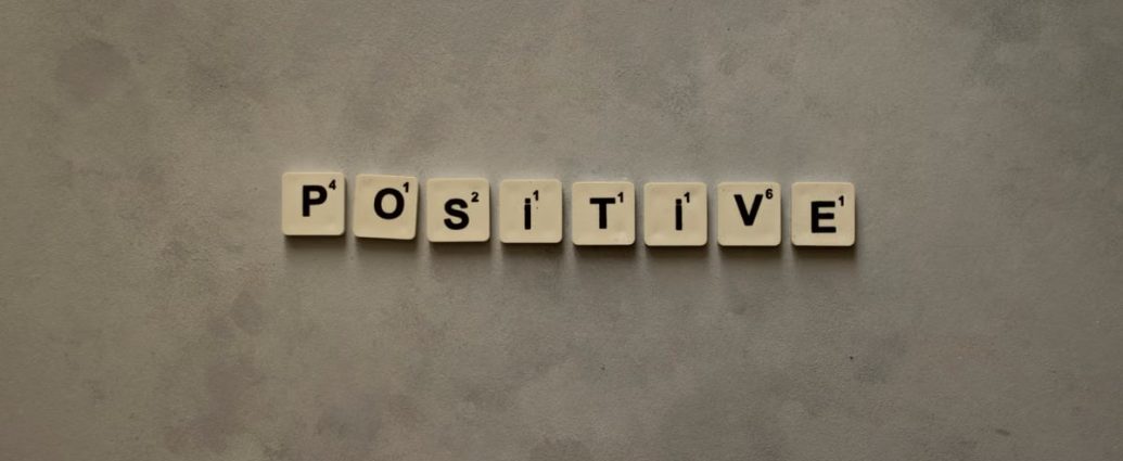 Scrabble tiles spelling 'Positive' on a textured surface, conveying optimism.