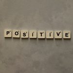 Scrabble tiles spelling 'Positive' on a textured surface, conveying optimism.