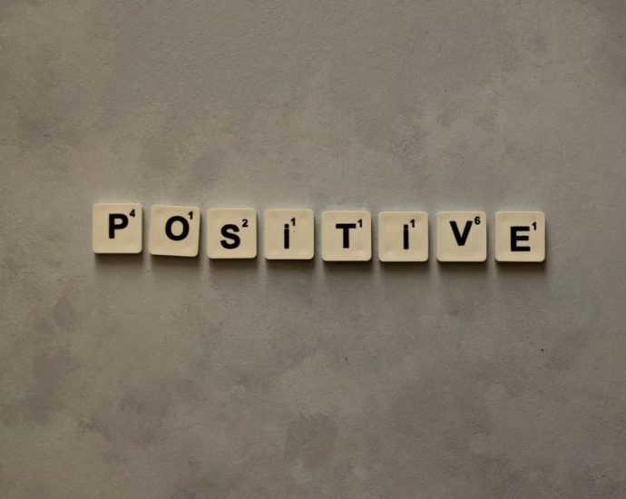 Scrabble tiles spelling 'Positive' on a textured surface, conveying optimism.